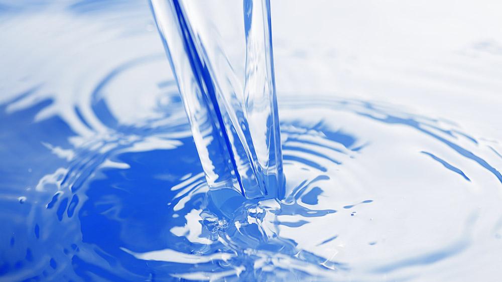 Clear water pouring into blue container